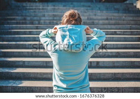 Girl prepairing for workout. Rear view of fit young woman in sports clothing standing on steps in morning. Female with muscular body ready for workout outdoors. Young woman standing by steps outdoors.