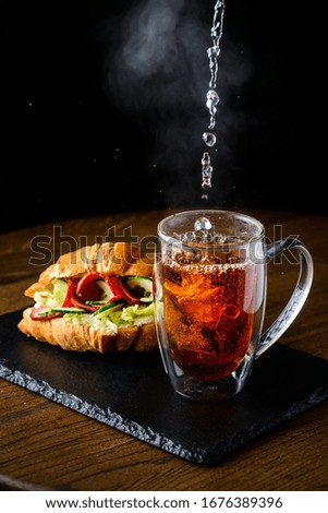 The process of brewing tea, pouring hot water from the kettle into the Cup, steam coming out of the mug, water droplets on the glass, hot tea is poured into a glass mug
