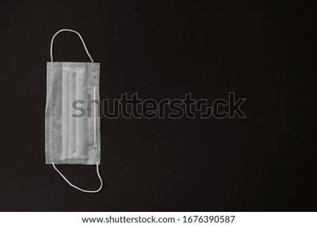 Surgical mask for personal protection isolated on a black background. Typical three-layer surgical mask for covering the mouth and nose. The procedure with a bacterial mask. Protection concept.