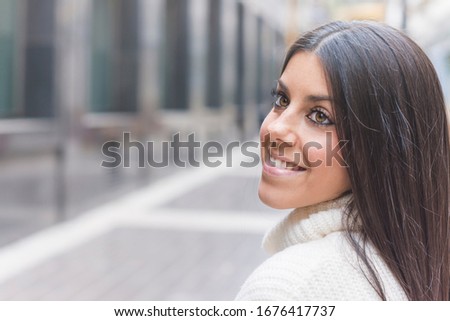Modern and smiling young girl posing on the street
