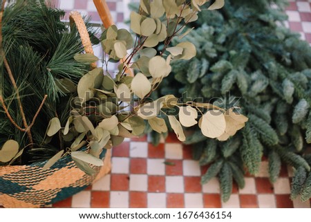 Base for Christmas wreath. Christmas decorations. Florist making Christmas wreath. View of female hands make a wreath. Decorations for wreath. Oranges, flowers red berries, wooden stars.