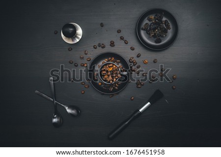 An espresso mug filled with coffee beans, surrounded by utensils and ingredients
