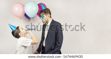 Two guys joyfully posing during their birthday. Two guys with balloons. They are smiling. Hat cone, glasses, whistles. Banner. Place for text
