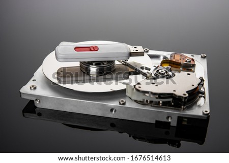 Computer hard drive and flash drive on a gray-black gradient background, with a mirror image. The concept of open and new high-tech technologies in the modern world.