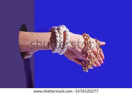 Pair of hands tied by rope and golden chain