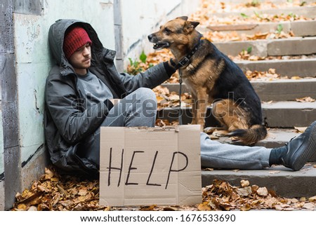homeless man with a dog and a sign