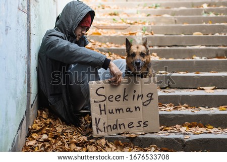homeless man with a dog and a sign