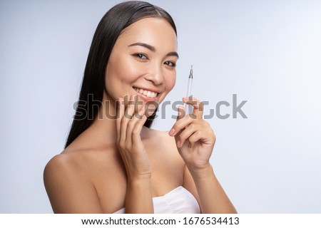 Waist up of smiling young female posing with acne loop in studio. Isolated on white background. Beauty and health concept
