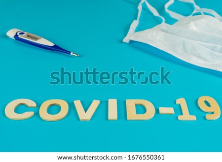 Medical equipment with mask and covid-19 thermometer on blue background
