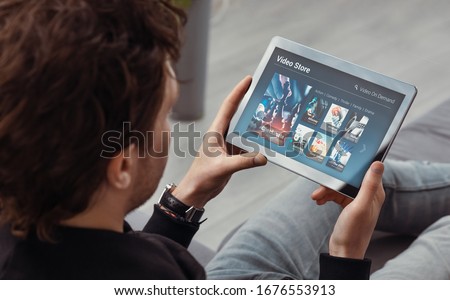 Man using tablet for watching VOD service. Video On Demand television concept Royalty-Free Stock Photo #1676553913