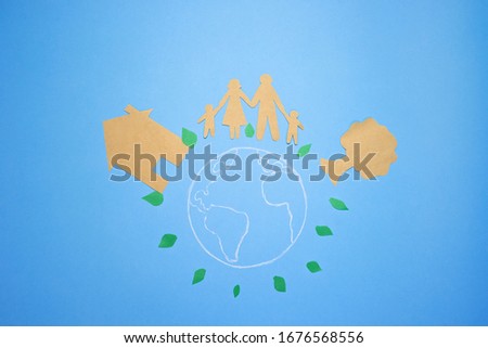 Image of planet Earth on blue background. Family paper and tree cutout. Earth day. Environmental green energy, eco friendly, save the environment concept. Abstract paper art scene. Top view, flat lay.