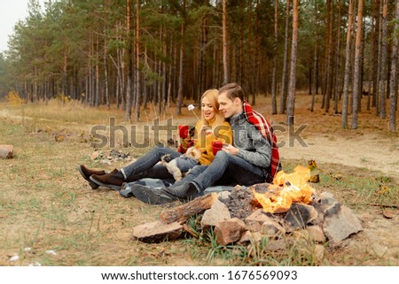 happy couple in love at a picnic with bonfire. couple playing with their little dog. the couple enjoys communication and time together
