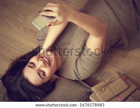 Top view of a woman using her phone while lying on her back
