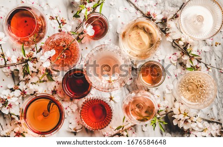 Various shades of rose wine. Flat-lay of rose wine in different colors in glasses and spring blossom flowers over marble background, top view. Wine shop, bar, tasting, seasonal wine list concept Royalty-Free Stock Photo #1676584648
