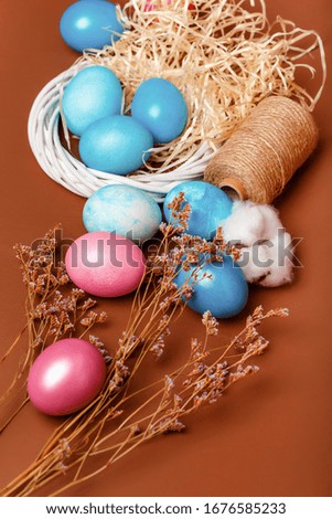Easter composition with dyed eggs in the nest on a brown background. Blue and pink Easter eggs. Colored eggs in the nest. Rustic composition with easter atmosphere.