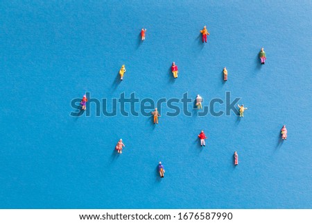 Miniature people social distancing concept to avoid coronavirus covid-19 sars-cov2 spread aroung the country Small miniature people on colored background distanced each other. Diffusion of coronavirus Royalty-Free Stock Photo #1676587990