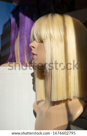 Mannequin with a blonde wig in a shop window with a vertical line of a shadow in Peterborough,Uk.