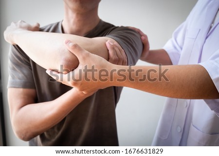 Therapist treating a male injured by rotator cuff stretching method, Physical therapy concept. Royalty-Free Stock Photo #1676631829