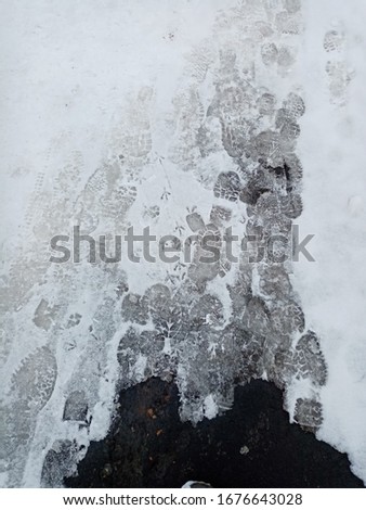Snowy road with traces of birds and people spring and winter abstract background with copy space