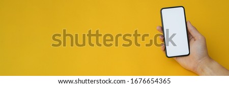 Cropped shot of a man holding blank screen smartphone on yellow background can be used for banner 