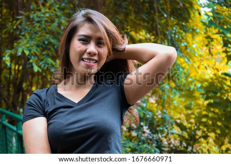 Young female wearing black t shirt do a posing in the park. Suitable for mock up design template