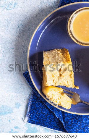 Plate with two pieces of pumpkin cheesecake and with caramel topping on a blue ceramic plate, light blue stone background. Selective focus. Top view.