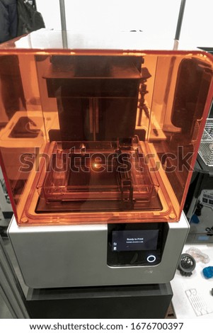 3D printer under a red plastic protective glass