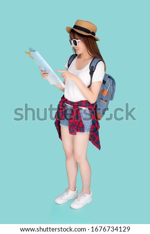 Beautiful happy young asian woman travel looking and pointing a paper map isolated on blue background, asia girl search journey with direction in vacation trip with cheerful for leisure.