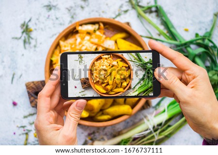 Phone photo of food. Smartphone picture of baked, grilled potato. Woman hands. Take photography of vegan, vegetarian healthy meal. For food blogging style