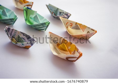 Banknotes rolled up in the form of ships. Revenues and expenses of shipping and cruise companies. Light background, vignetting.