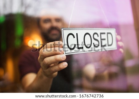 small business, people and crisis concept - owner puts closed sign at bar or restaurant glass door or window Royalty-Free Stock Photo #1676742736