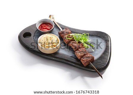 Marbled beef skewer side view. Delicious kebab with sauce and noodles on wooden tray. Grilled meat with tasty garnish. Spicy meal with onion. Restaraunt dish, roasted food composition
