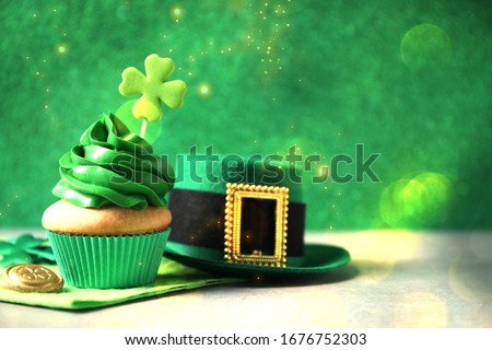 Decorated cupcake, hat and coin on grey table, space for text. St. Patrick's Day celebration