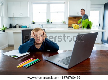 Coronavirus Outbreak. Lockdown and school closures. School boy with face mask watching online education classes feeling bored and depressed at home. COVID-19 pandemic forces children online learning. Royalty-Free Stock Photo #1676760499