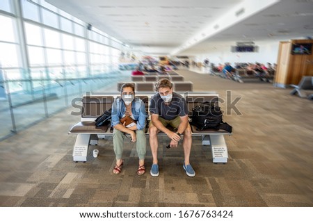Coronavirus outbreak travel restrictions. Travelers with face mask at international airport affected by flight cancellation and travel ban. COVID-19 pandemic and countries lockdowns and shutdowns. Royalty-Free Stock Photo #1676763424