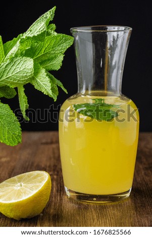 Close-up of lemon pitcher with slices and mint on dark wooden table in vertical