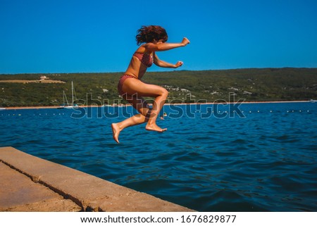 A young tourist jumping into the sea in the town of Punta in Croatia