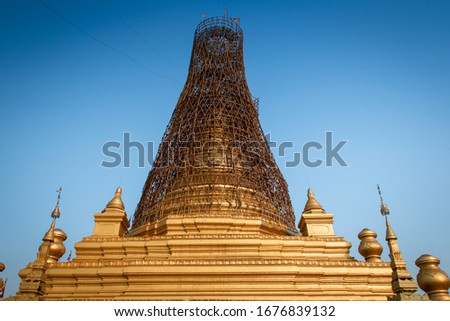 Golden Sandamuni Pagoda, Mandalay, Myanmar. Central dome or Zedi under scaffolding during restoration work, against a clear blue sky background