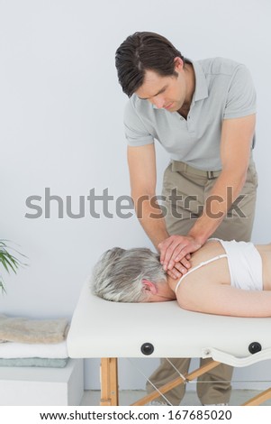 Male physiotherapist massaging a senior woman's back in the medical office