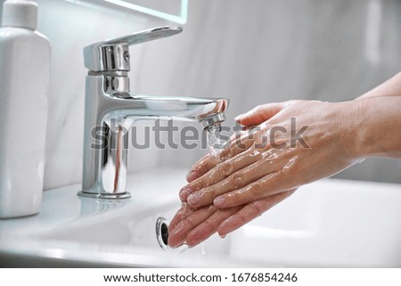 Young woman washing hands with soap over sink under faucet with water in bathroom. Girl doing cleaning hygiene routine to prevent coronavirus infection,disinfect skin care, microbe protection concept.