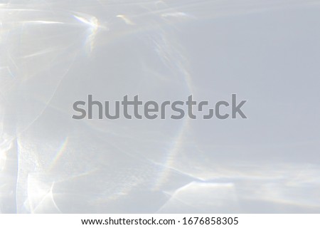 Water texture overlay effect for photo and mockups. Organic drop diagonal shadow caustic effect with rainbow refraction of light on a white wall. Royalty-Free Stock Photo #1676858305