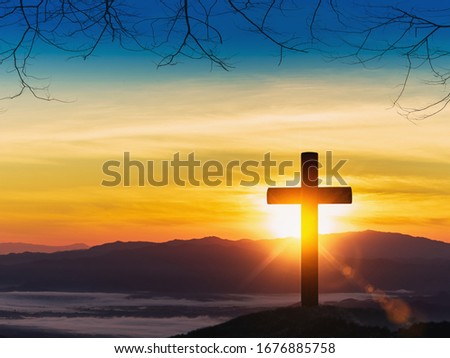 Silhouette of cross on mountain sunset background.