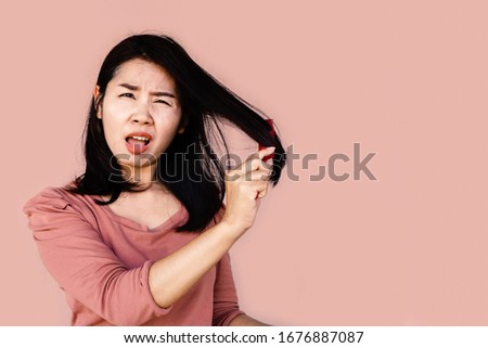 unhappy Asian woman using comp brushing her dry damaged long hair  Royalty-Free Stock Photo #1676887087