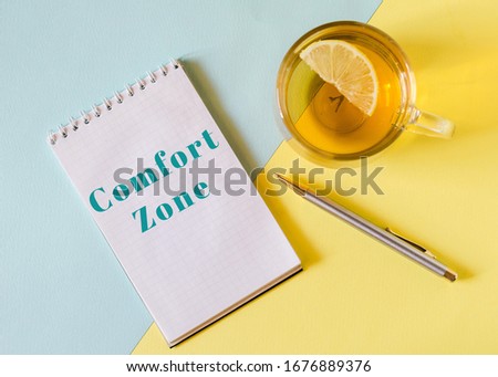 Written text COMFORT ZONE on a notebook and pen, lemon tea yellow and blue background