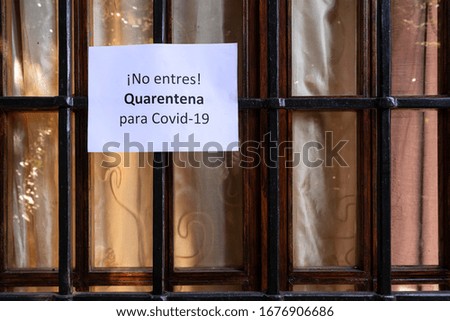 The sign with the prohibition of entry for Quarantine for the Covid-19 virus in spanish language on a home window