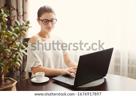 Young concentrated woman enjoying work on laptop. Positive female student doing homework, watching online webinar, listening audio course, writing emails, distantly working with wifi 