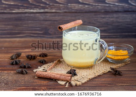Masala tea or a traditional Indian drink with milk and spices, useful in winter to enhance immunity. On a wooden background.