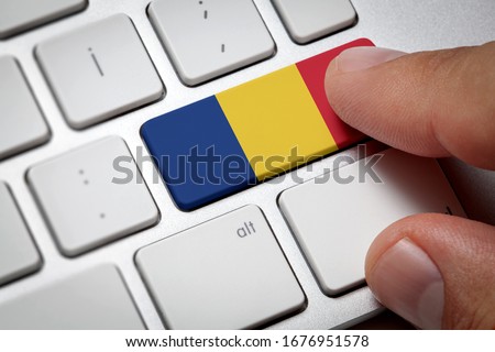 Online International Business concept: Computer key with the Romania flag on it. Male hand pressing computer key with Romania flag.