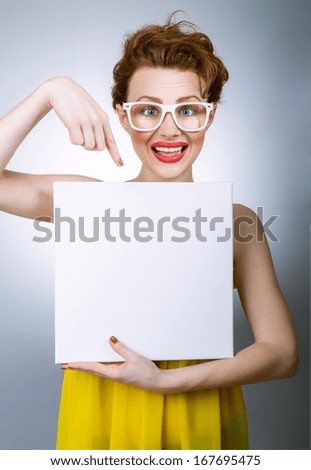 Young cheerful woman showing her finger on blank white board