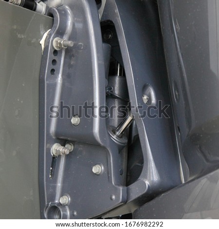 Boat outboard motor transom stationary mounting suspension close up, clamp, nuts, hydraulic trim and tilt cylinder different control Royalty-Free Stock Photo #1676982292